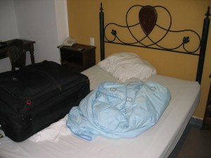 a bed with a blanket and luggage