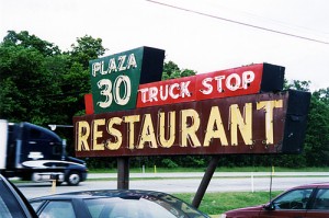 a restaurant sign with a truck driving down the street