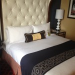 a bed with a white headboard and a black and white pillow