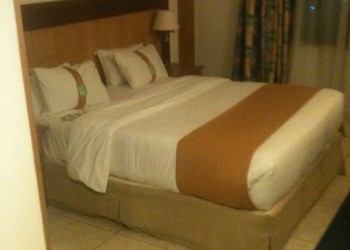 a bed with white sheets and brown blanket