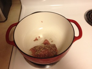 a red pot with a piece of meat in it