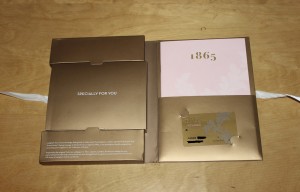 a gold box with a pink card inside