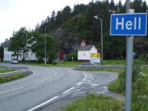 a road with a sign and a house in the background
