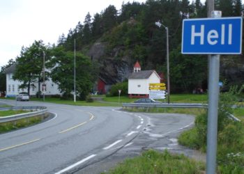 a road with a sign and a house in the background