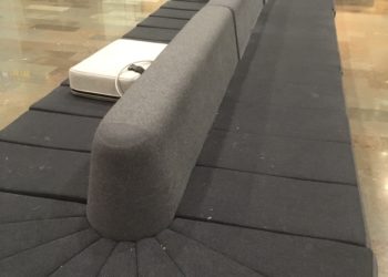 a long grey couch with a white object on top