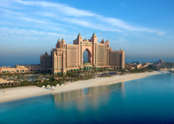 a large building with a beach and palm trees with Atlantis, The Palm in the background