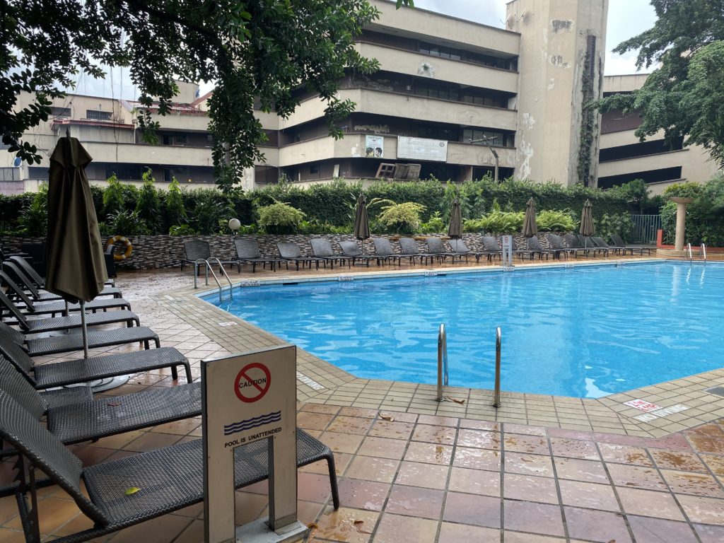 a pool with chairs and umbrellas in front of a building