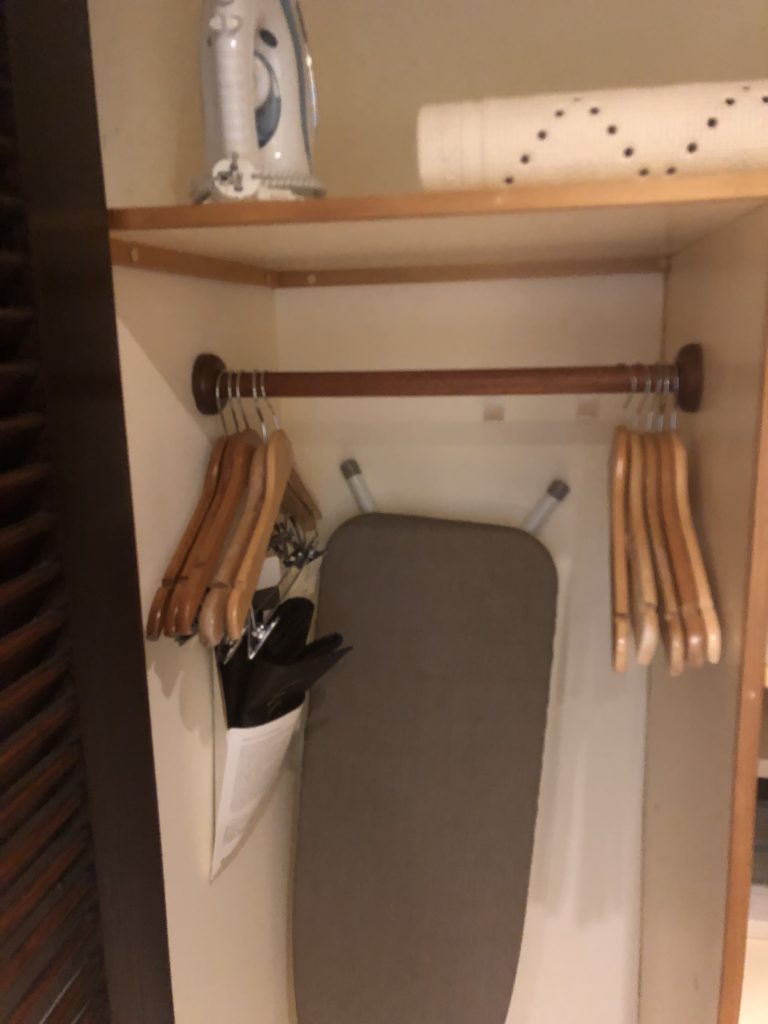 a closet with ironing board and swingers