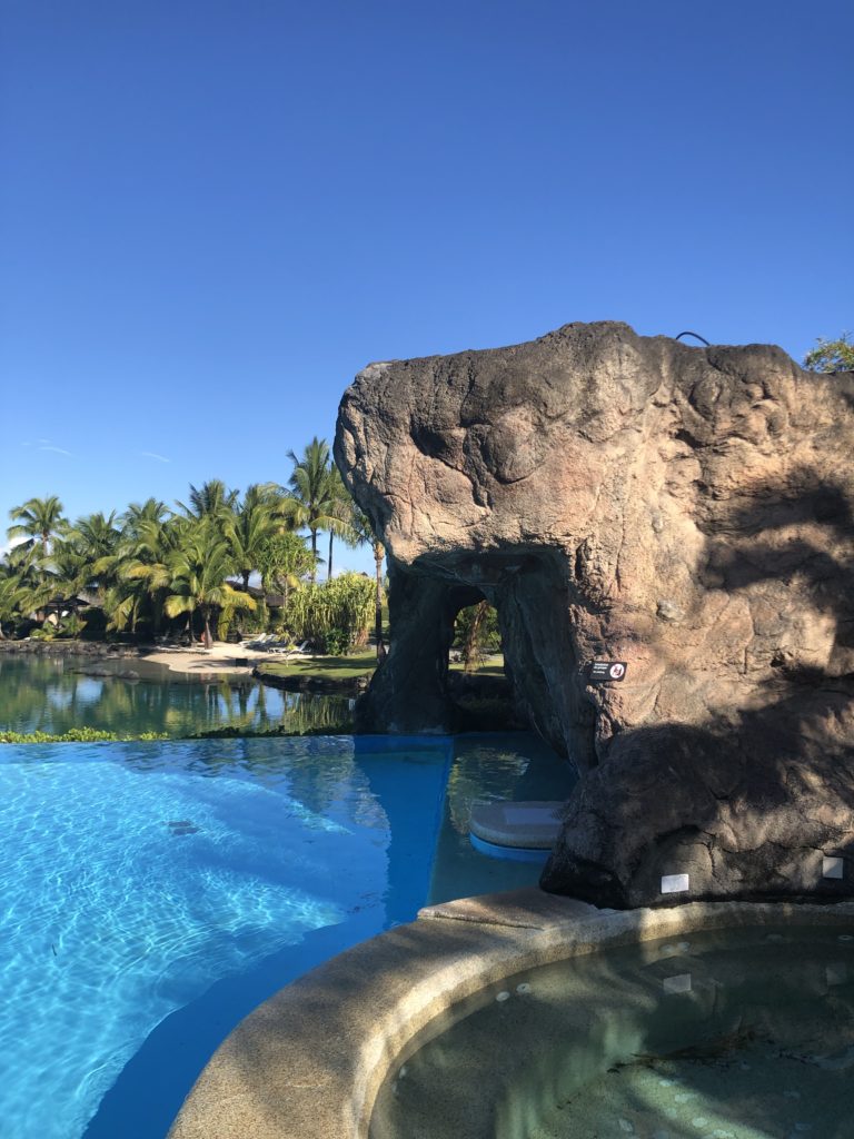 a pool with a rock formation and a body of water