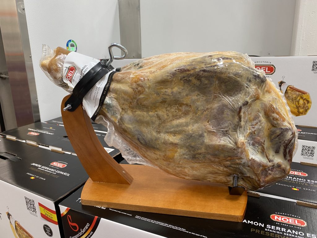 a piece of meat wrapped in plastic on a wooden stand