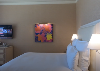 a bed with white sheets and a painting on the wall