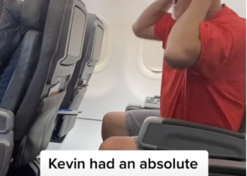a man in glasses screaming in an airplane