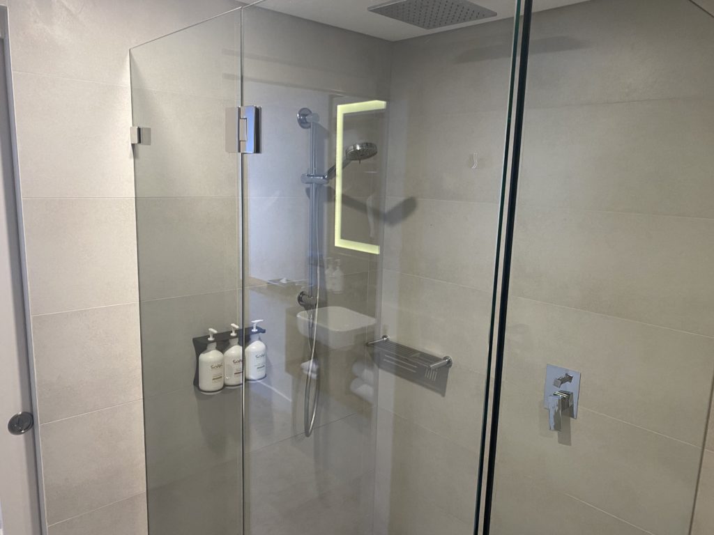 a glass shower with a sink and soaps