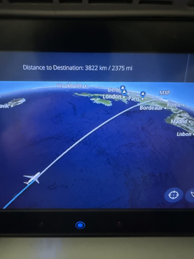 The image shows an in-flight entertainment screen displaying a flight map. The map indicates the plane's current position over the Atlantic Ocean, with a flight path leading towards Europe. Cities like Stockholm, Berlin, London, Paris, Bordeaux, Rome, and Lisbon are marked. The top of the screen shows the distance to the destination as 3822 kilometers or 2375 miles. An airplane icon is shown on the flight path.